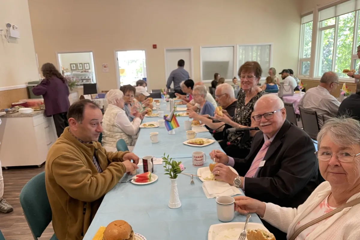 Friends around a long table at the church BBQ, plates full