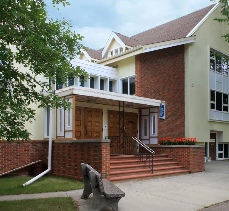 The front entrance of Highlands United Church on a summer day — brick steps up to the wooden doors under the porch