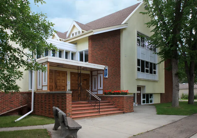 The front entrance of Highlands United Church on a summer morning, brick steps and wooden doors