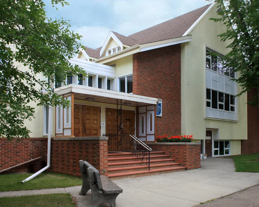 The front entrance of Highlands United Church on a summer morning, brick steps and wooden doors