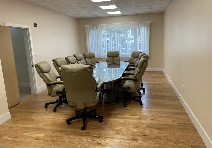 The Burrill Room set up boardroom-style with a long table, comfortable chairs, and bright windows