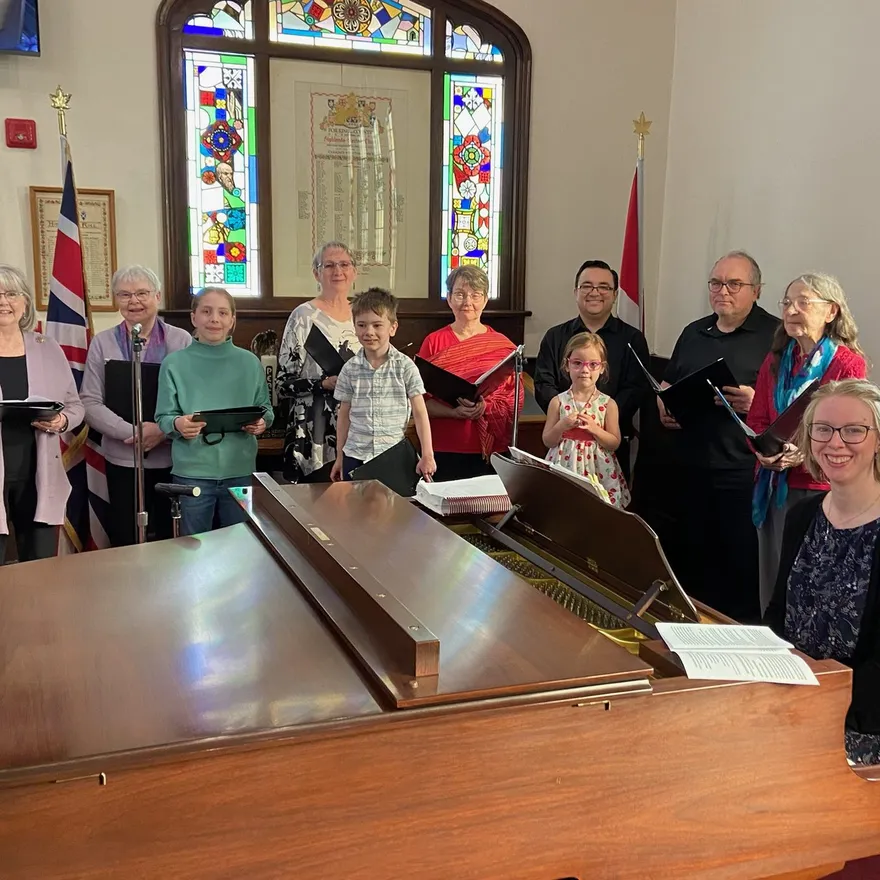 Singers of all ages gathered around the grand piano with Music Director Wendy Nieuwenhuis