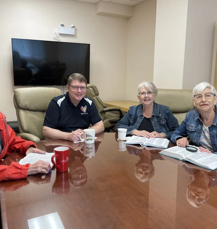 Four members of the Tuesday Conversation Group around the Burrill Room table, coffee in hand