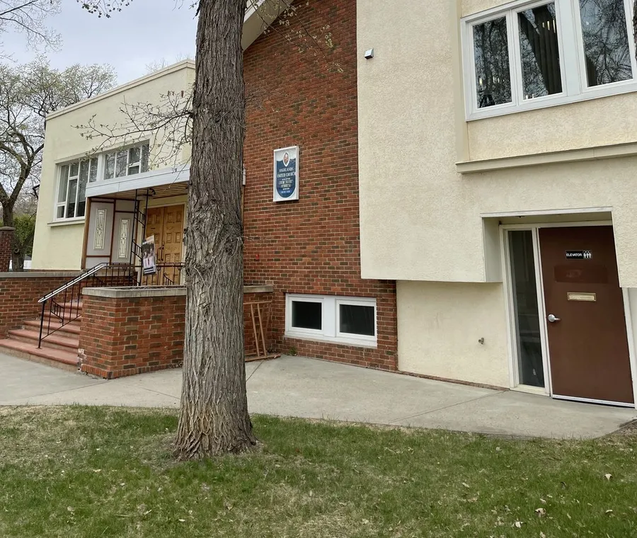 The church's accessible entrance under a big elm, with the elevator door at street level