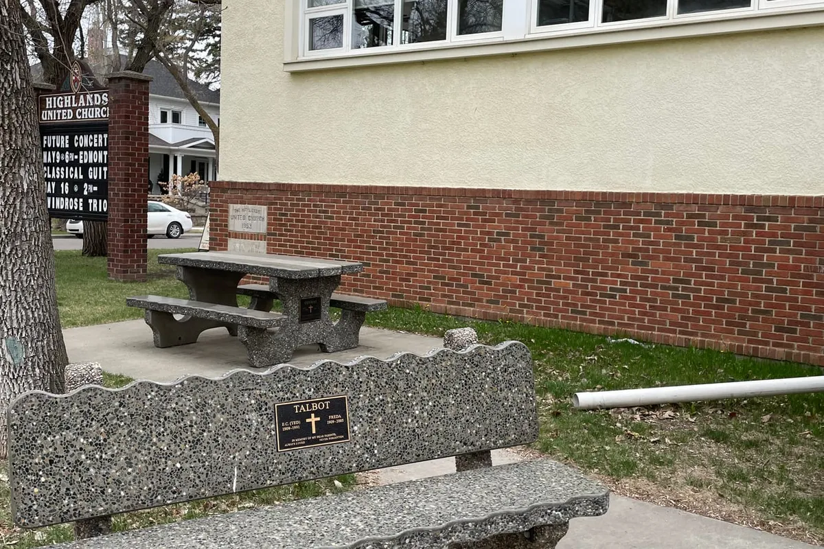 A memorial bench with a bronze plaque outside the church