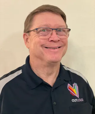 Portrait of Rev. Mervin Gallant, smiling, in an OUTLOUD polo shirt