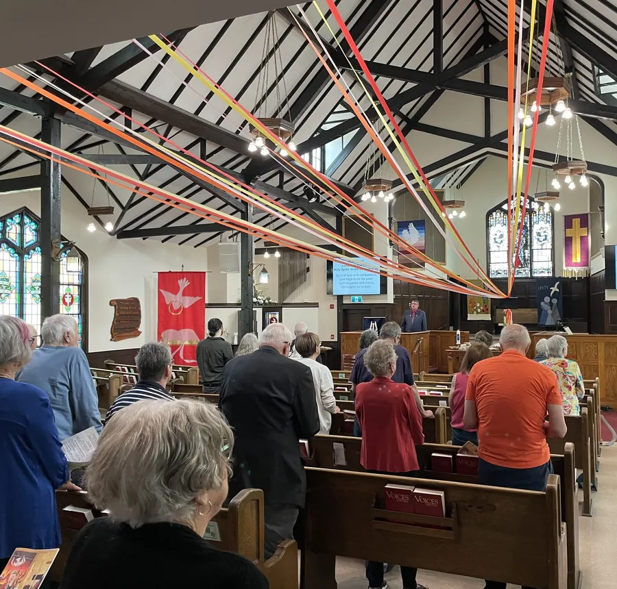 The congregation at a Pentecost service, with bright ribbons streaming from the sanctuary ceiling