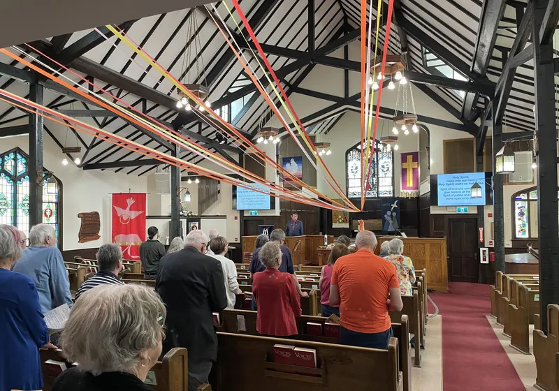 The congregation at a Pentecost service, with bright ribbons streaming from the sanctuary ceiling