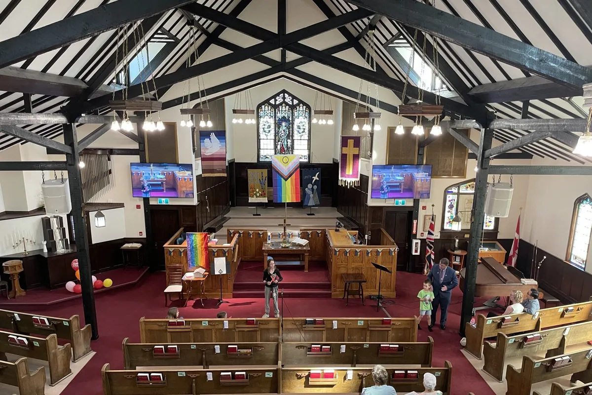 The sanctuary on a Sunday, children at the front under the rainbow flags