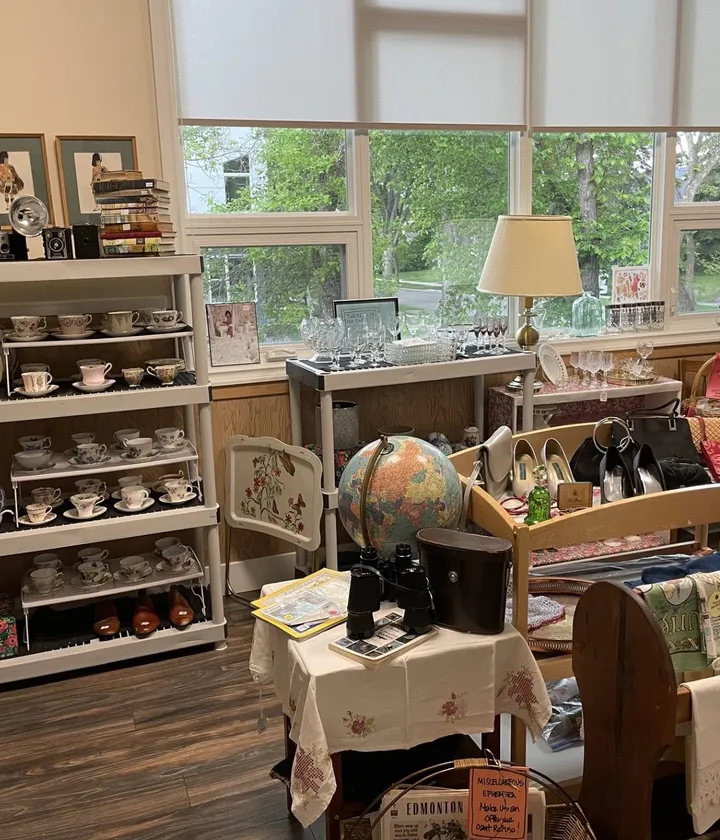 The sunlit Thrifted Gems boutique: shelves of teacups, a globe, vintage shoes, and linens
